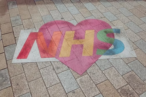 NHS logo written on brick on top of a red heart
