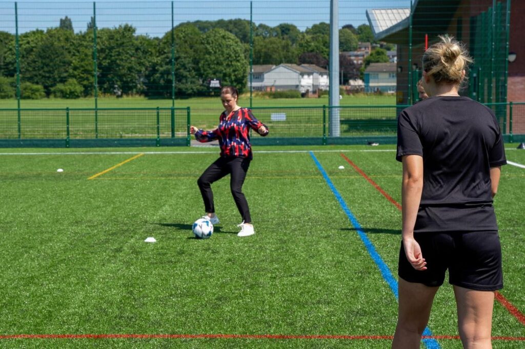 Stephanie Peacock MP on a football visit kicking a ball
